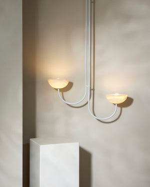 Modern asymmetrical pendant light fixture with two onyx shades on a neutral background