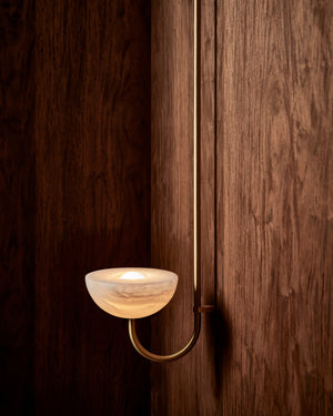 Modern wall-mounted light fixture with a glass shade on a wooden wall.