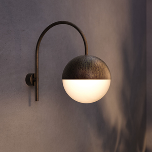 Outdoor Antique Brass Spherical Wall Light | Lighting Collective | curved arm turned on at night
