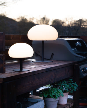 Two sizes of the outdoor lamps on a wooden surface with a scenic background