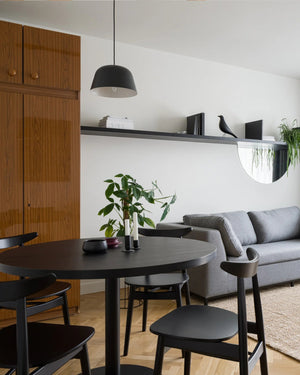 Modern living room with grey sofa, black dining table, and black pendant.