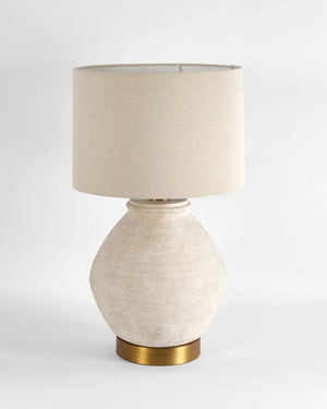 Table lamp with beige shade and textured white base on a light gray background