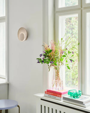 Wall light and a vase of flowers in a bright room