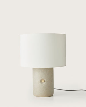 Table lamp with a white shade and beige base on a white background