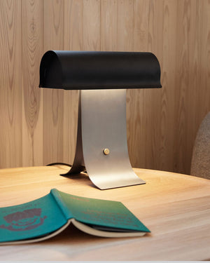 Scandinavian Arched Table Lamp Black Small on a wooden surface with a book underneath