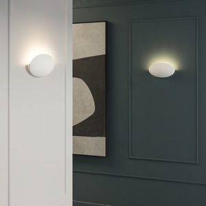 Two white plaster sculptural wall light mounted next to abstract painting and white wall light on
