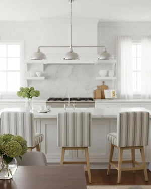 Modern kitchen with marble countertops, striped chairs, and a vase of flowers.