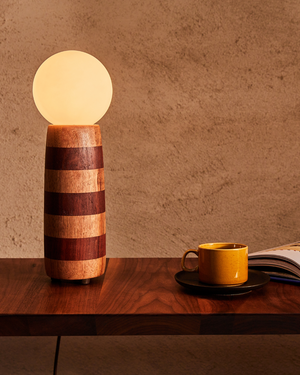 Timber Stripy Table Lamp | Buddy on a wooden table next to a cup and book against a brown background Vic Ash and Redgum