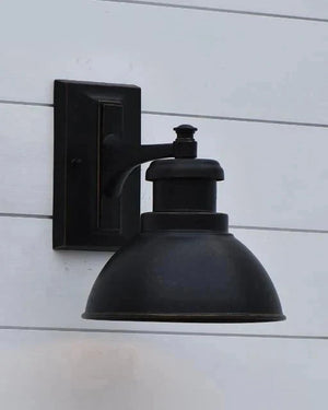 Black wall-mounted outdoor light fixture on a white wooden panel background