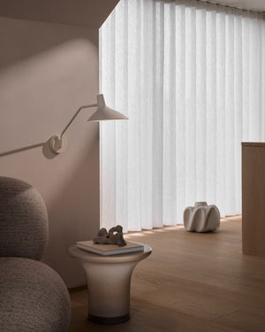 Modern interior with a lamp, small table, and decorative items in a room with large windows.