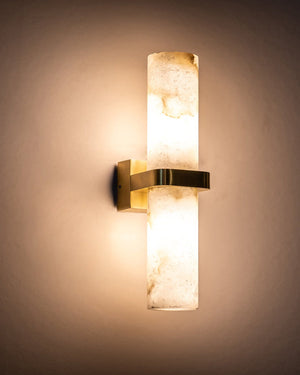 Alabaster sconce glowing on a warm plaster wall, throwing light up and down the surface
