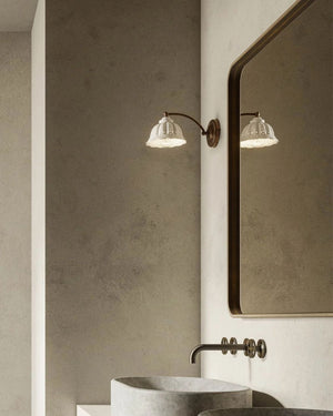 Curved arm and white perforated ceramic shade wall light on the side of a mirror in a bathroom 