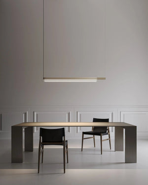 An architectural ribbed glass linear pendant hanging above a table in a minimal living room space