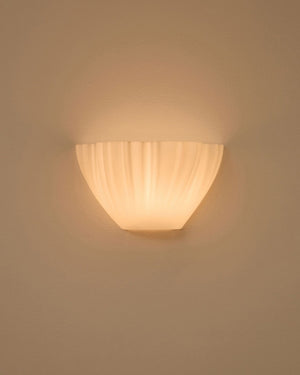 Semicircular wall light with an organic shape and textured folds illuminated on beige background