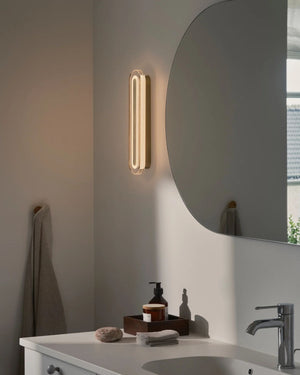 Art Deco Bathroom Wall Light in brass mounted vertically beside a round mirror above a bathroom vanity