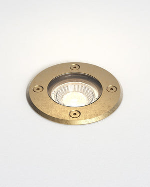Brass-colored round light fixture on a white background