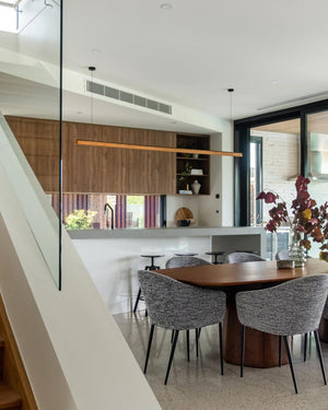 Modern dining area with wooden cabinetry and a timber linear pendant