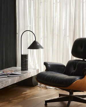 Black marble table lamp with arched arm on console beside Eames lounge chair in contemporary living room