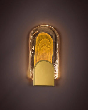 A modern wall sconce with a yellow golden bubble layered glass with brass holder 