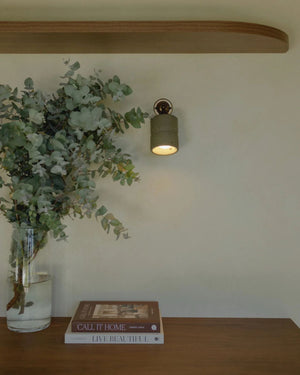 Cast Concrete Wall Sconce in moss finish with antique brass knuckle mount above timber desk in organic contemporary interior