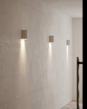 Indented ceramic wall lights styled along a minimalist hallway