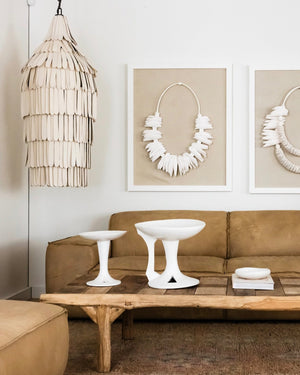 Ceramic cocoon shard pendant light hanging in a living room next to leather sofa and framed art