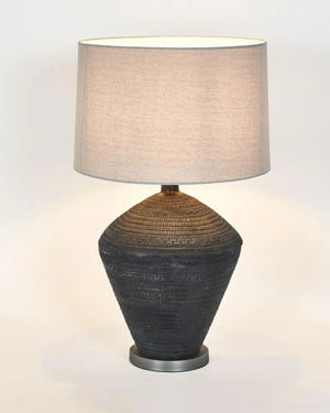 Ceramic Vessel Table Lamp with incised woven texture base and natural linen drum shade, lit on warm white background