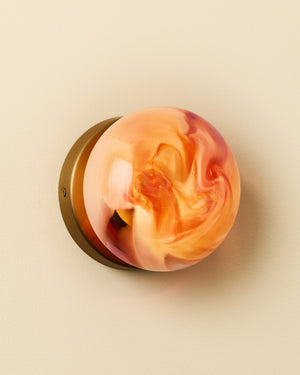 Decorative wall sconce with a marbled rosa finish on a beige background