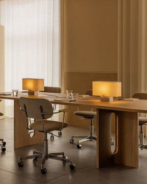Two compact aluminium based table lamps with warm glowing light placed on a warm wooden table in a modern office 