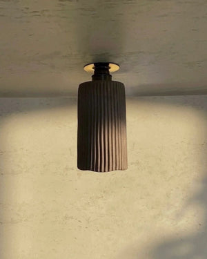 Concrete Wavy Downlight in charcoal mounted on ceiling casting warm downward light in atmospheric interior