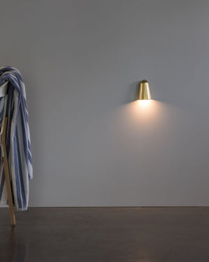 Gold wall-mounted lamp on a gray wall.