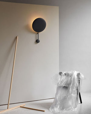 Modern black wall-mounted light fixture on a neutral background