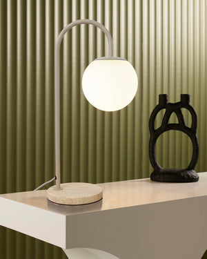 Modern orb glass table lamp with a opal globe shade on a wooden base next to a black abstract sculpture 
