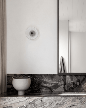 Modern bathroom with marble countertop, white sink, and framed mirror, glass wall light