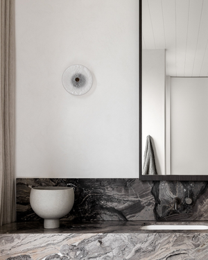 Modern bathroom with marble countertop, white sink, and framed mirror, glass wall light