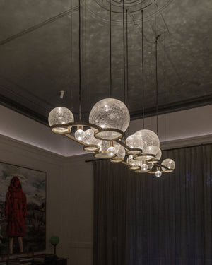 Modern chandelier with glass globe lights in a dimly lit room.