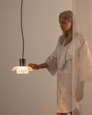 Woman in a white outfit holding a modern pendant light crackle glass designed by ADesignStudio