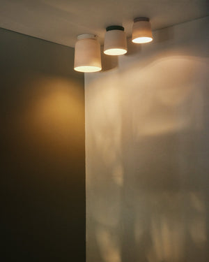 Three ceiling lights casting shadows on a wall