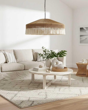 A boho style Dome raffia cotton tassel pendant pendant light with cream tassels hanging in a living room above a round coffee table.