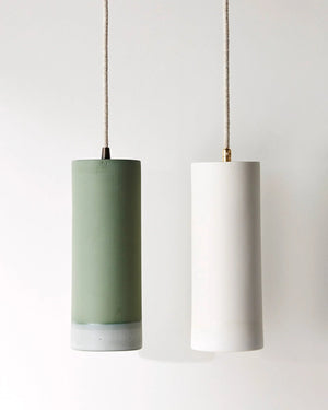Two pendant lights, one green and one off-white, hanging against a plain background.