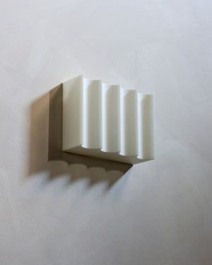 Modern wall light with textured shade on a beige background