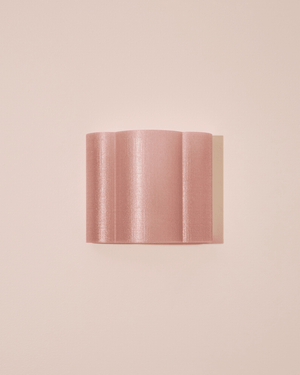 3D printed wall-mounted sconce with a fluted, pleated design in a shimmering dusty pink metallic finish