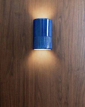 Short curved wall light with indents on the bottom in snow cone finish