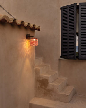 Staircase with a wall-mounted lamp casting light on a textured wall.