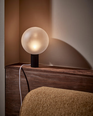 Table lamp with a spherical glass shade on a wooden surface.