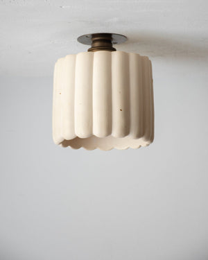 Ceiling light fixture with ribbed design on a plain background