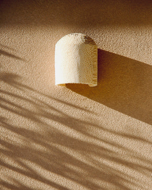 Beige ceramic light on a textured beige surface with shadow