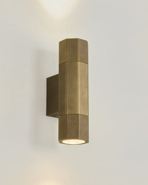 Geometric Outdoor Brass Wall Light mounted on a white wall with warm light on