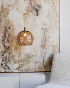 Decorative pendant light hanging in front of a textured wall