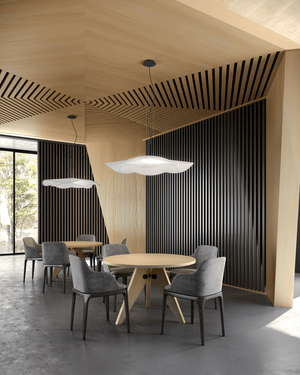 Modern dining area with round table and gray chairs in a room with wooden ceiling and black striped walls.
